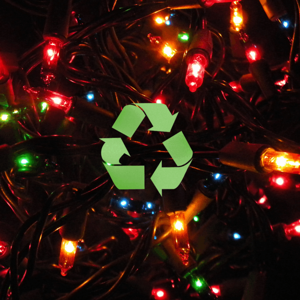 Close-up photo of tangled holiday string lights glowing red, green, blue, and yellow in the dark. A large green recycling symbol is centered over the lights.