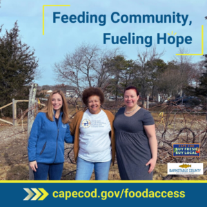 Three smiling women stand together in an outdoor community garden. One woman wears a blue jacket, another wears a white t-shirt with a Cape Verdean Cultural Center logo, and the third wears a gray dress. The text "Feeding Community, Fueling Hope" is displayed above them, with a yellow and blue banner below that reads "capecod.gov/foodaccess." The Cape Cod Buy Fresh Buy Local and Barnstable County logos appear in the bottom right corner.