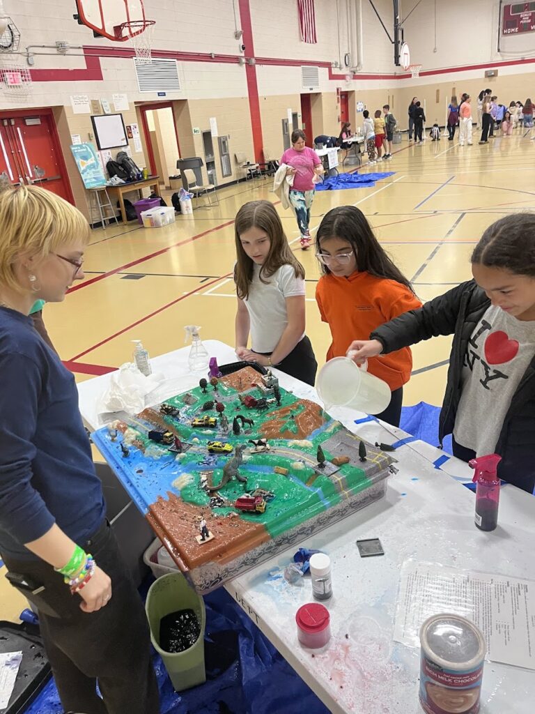 Students participate in an Enviroscape demonstration showing how pollution moves through a watershed.